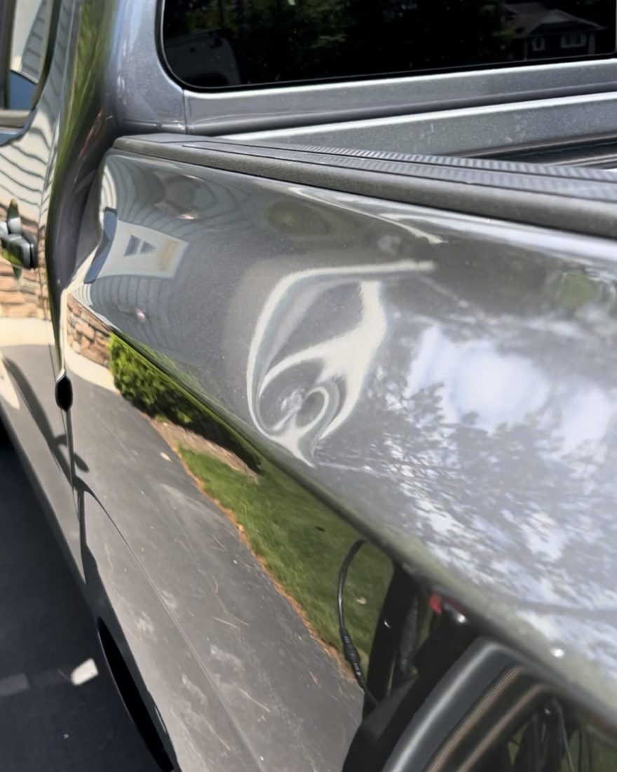 Before: a deep dent in the gray bedside of a Nissan Frontier