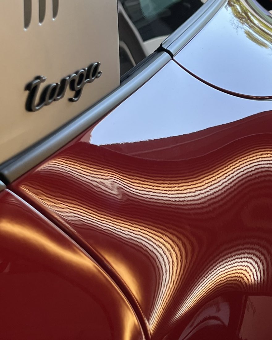Before: the stripes wobble over a dent in the red rear fender of a Porsche 911 Targa