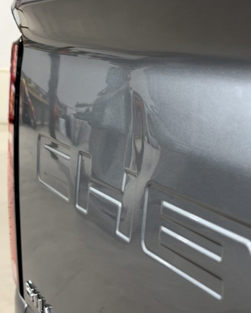 Before: a dent beside the lettering on a silver Silverado tailgate