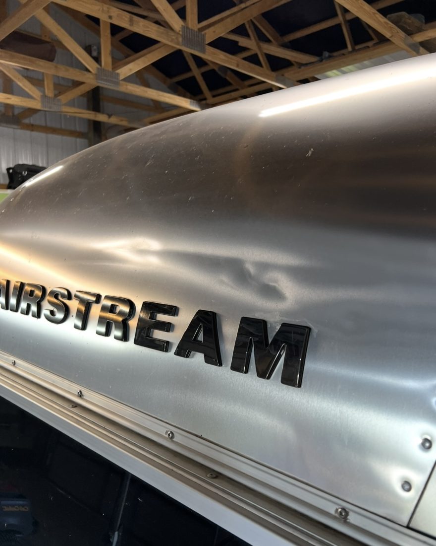 Before: a wide shallow dent in the aluminum front end of an Airstream trailer