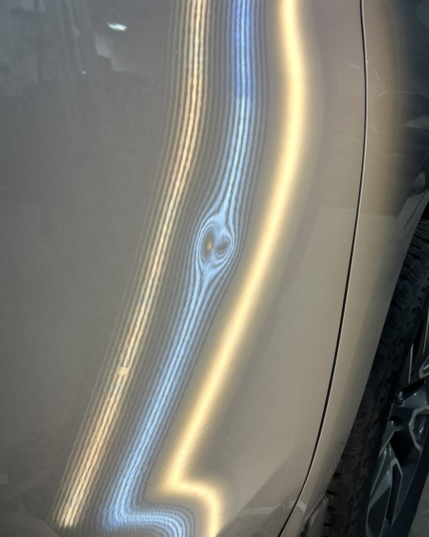 Before: a crease breaks the stripes on a silver door