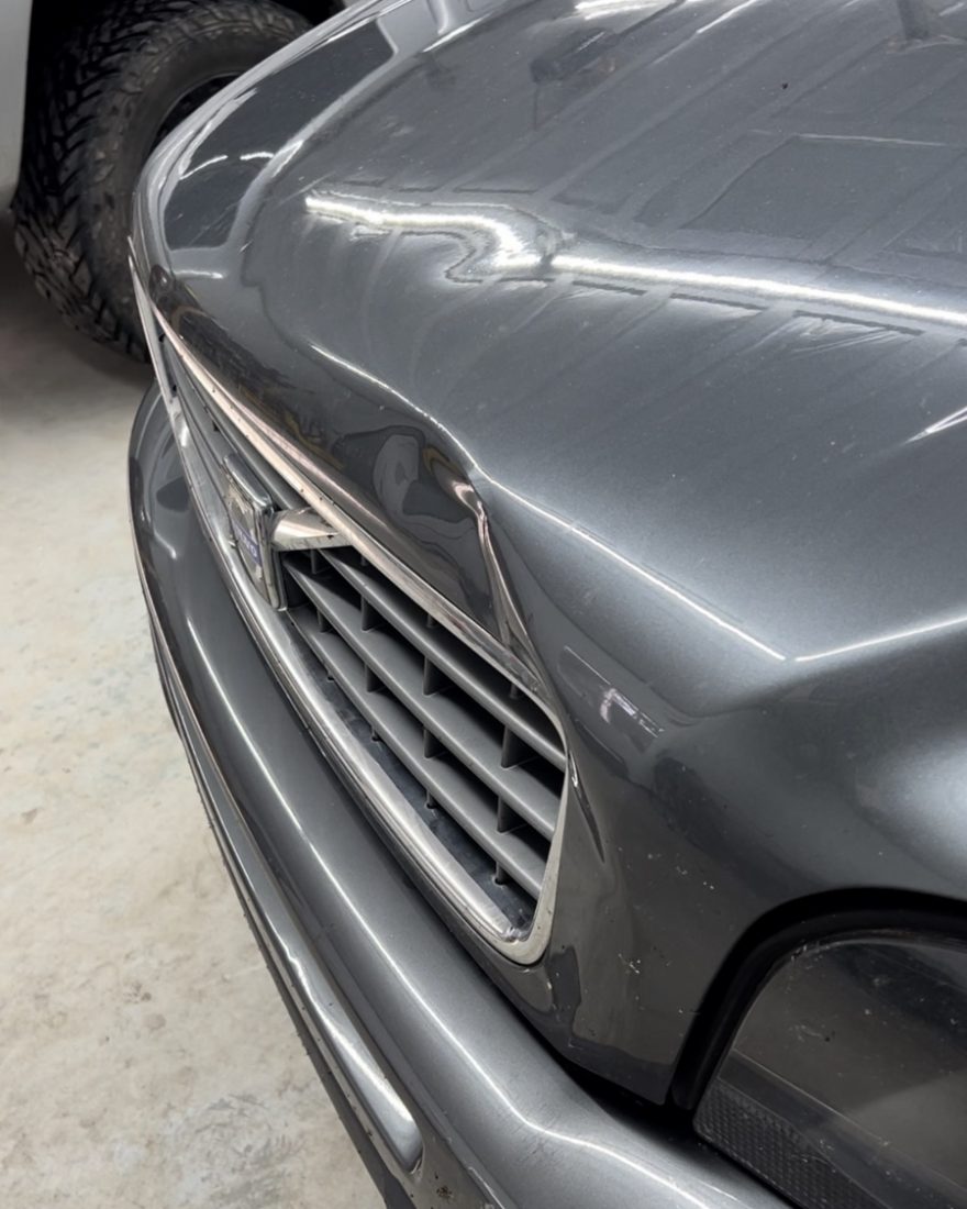 Before: a large dent in the front fender of a gray Volvo